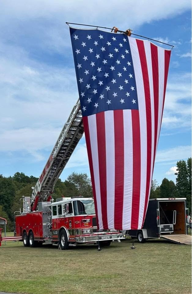 A large American flag hanging from the department's aerial ladder truck.